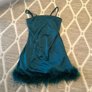 A aqua marine long dress with feathers around the brim.